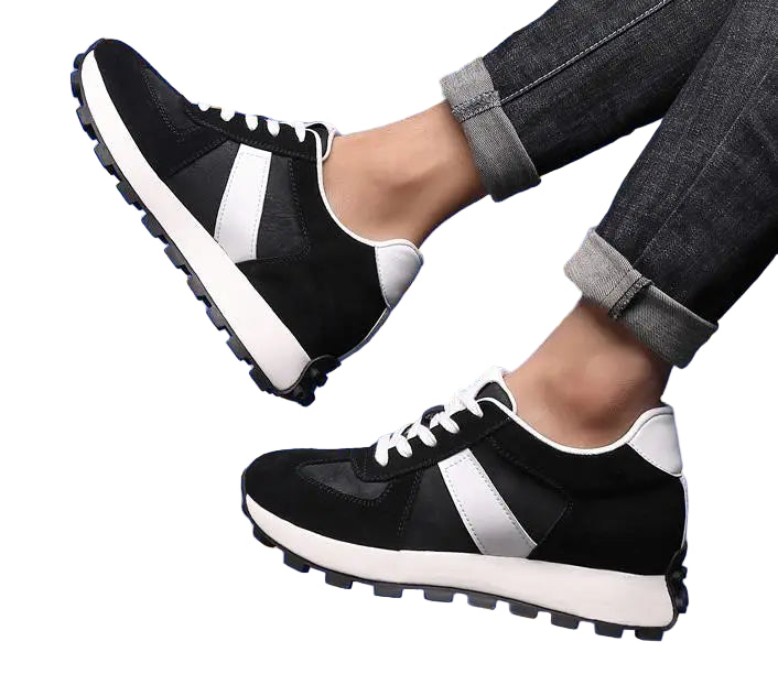 Black and white sneakers worn with rolled-up jeans on a blue tiled background