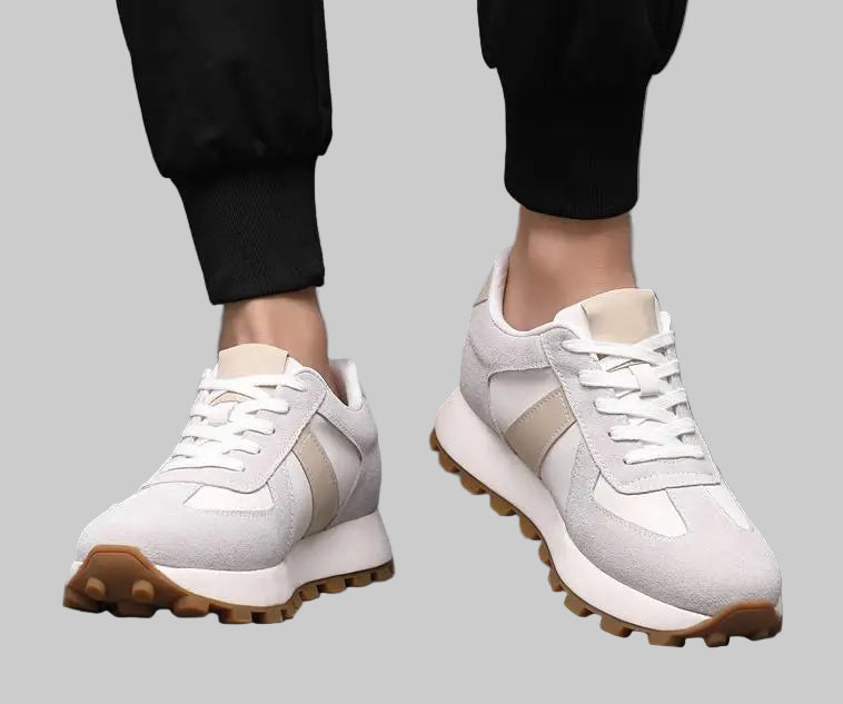 White sneakers with brown soles worn by a person on a gray background